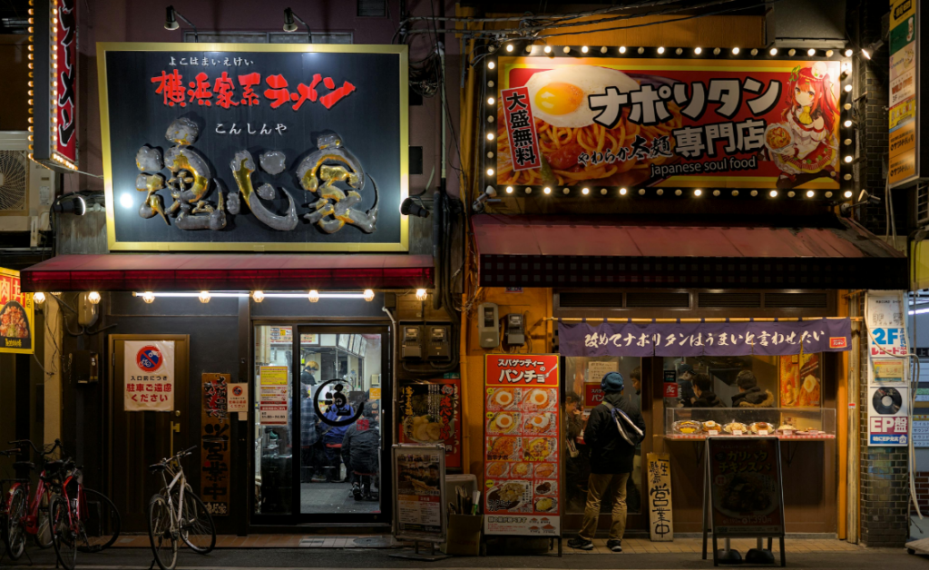 Two restaurants in an urban setting, one with a sign in Japanese characters and the other featuring a menu of Japanese soul food.