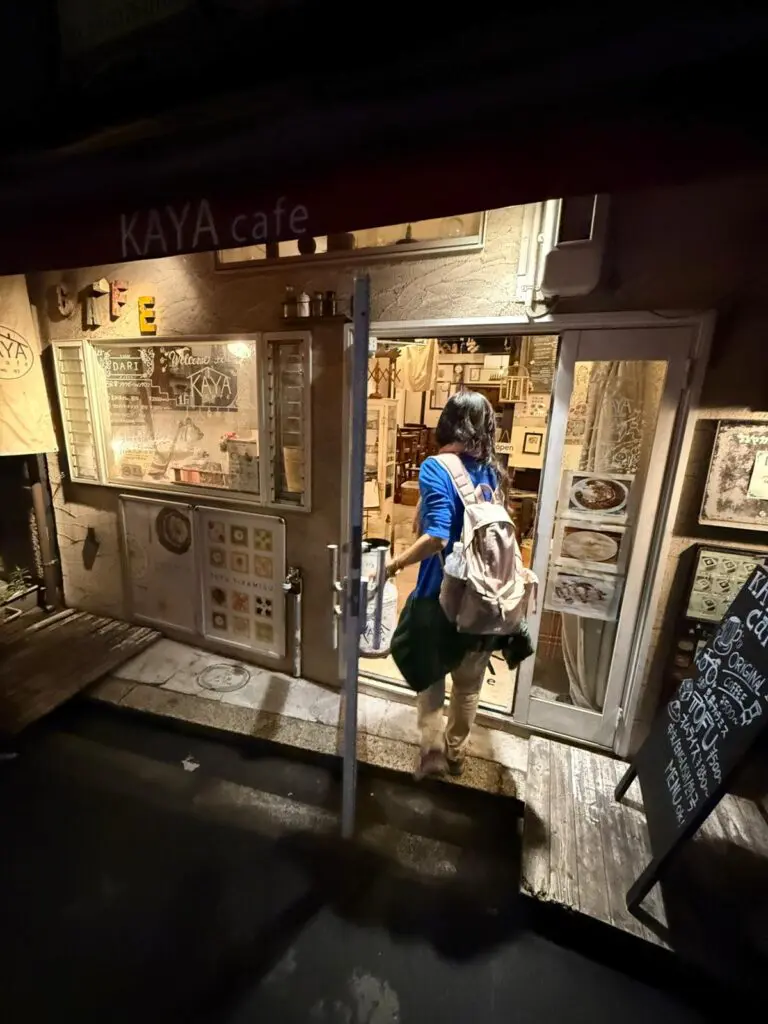 10 Hidden Gems in Osaka: Uncover Secret Spots Beyond Dotonbori 16 Person entering Kaya Cafe, a small establishment with a welcoming entrance and various framed artworks displayed on the walls.