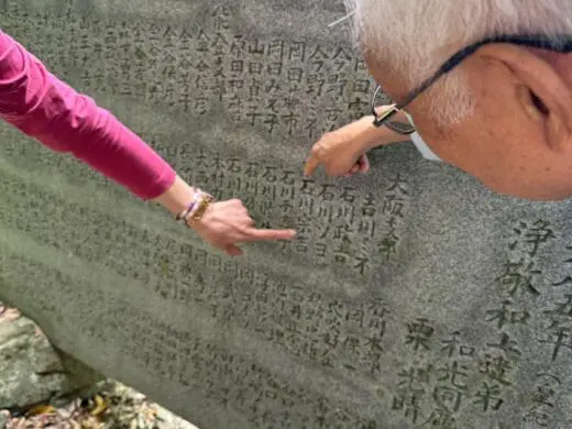 Kyoto Hidden Gems walking tour moment beside a gray stone marker with engraved Japanese characters, with Scott pointing out details for a local guide experience.