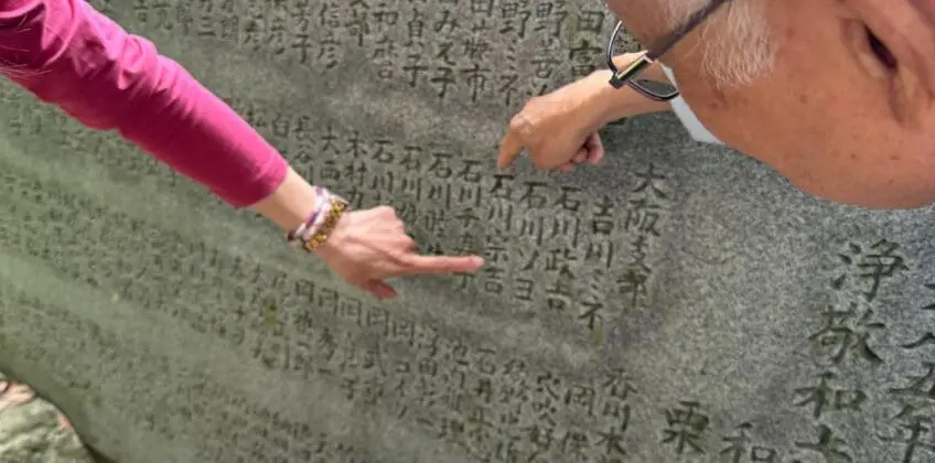 Kyoto Hidden Gems walking tour moment beside a gray stone marker with engraved Japanese characters, with Scott pointing out details for a local guide experience.