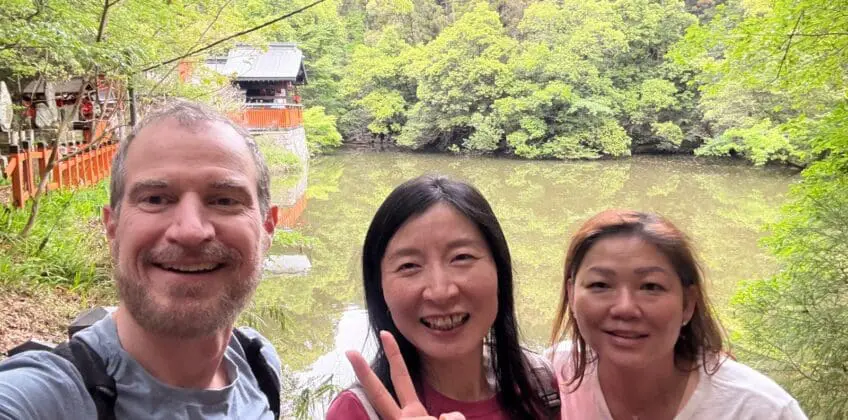 On a Kyoto Hidden Gems tour, Scott and Theresa smile by the Kodama Ike pond near Fushimi Inari Shrine, framed by lush green trees along a quiet trail.Kyoto Hidden Gems Tour