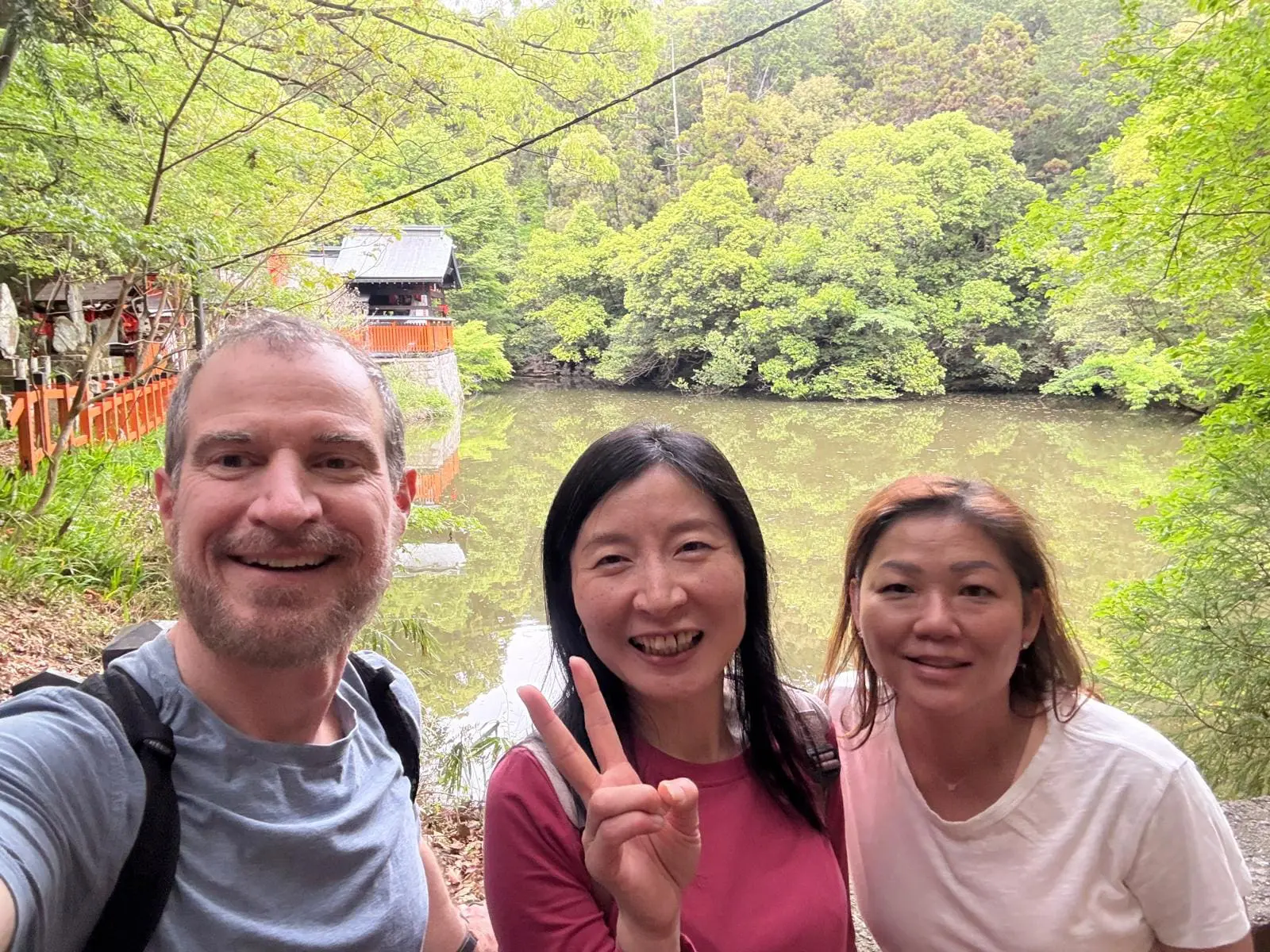 On a Kyoto Hidden Gems tour, Scott and Theresa smile by the Kodama Ike pond near Fushimi Inari Shrine, framed by lush green trees along a quiet trail.Kyoto Hidden Gems Tour