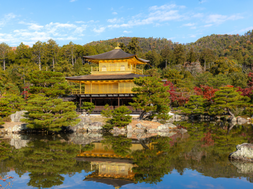 Kiyomizu-dera temple pagoda framed by crimson and orange autumn foliage against a bright blue Kyoto sky, capturing Kyoto’s historic fall scenery in Japan.