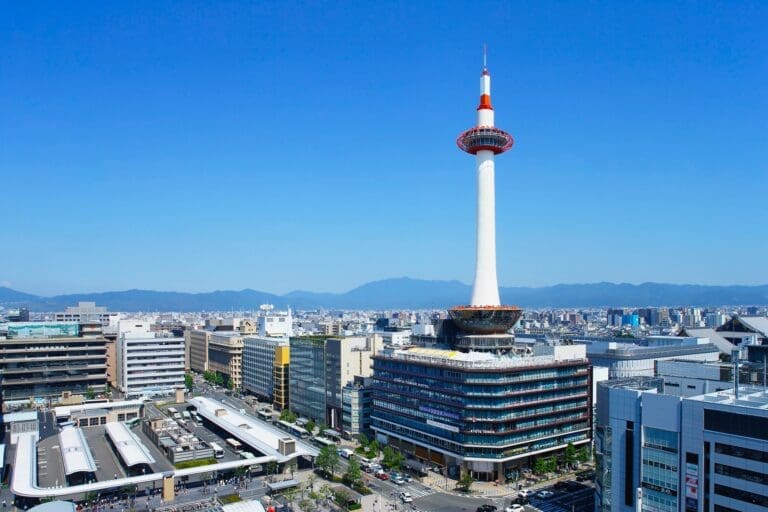 12 Most Enjoyable Indoor Things to Do in Kyoto for Culture & Fun 17 Kyoto Tower standing prominently above the surrounding buildings in Kyoto, Japan, against a clear blue sky.