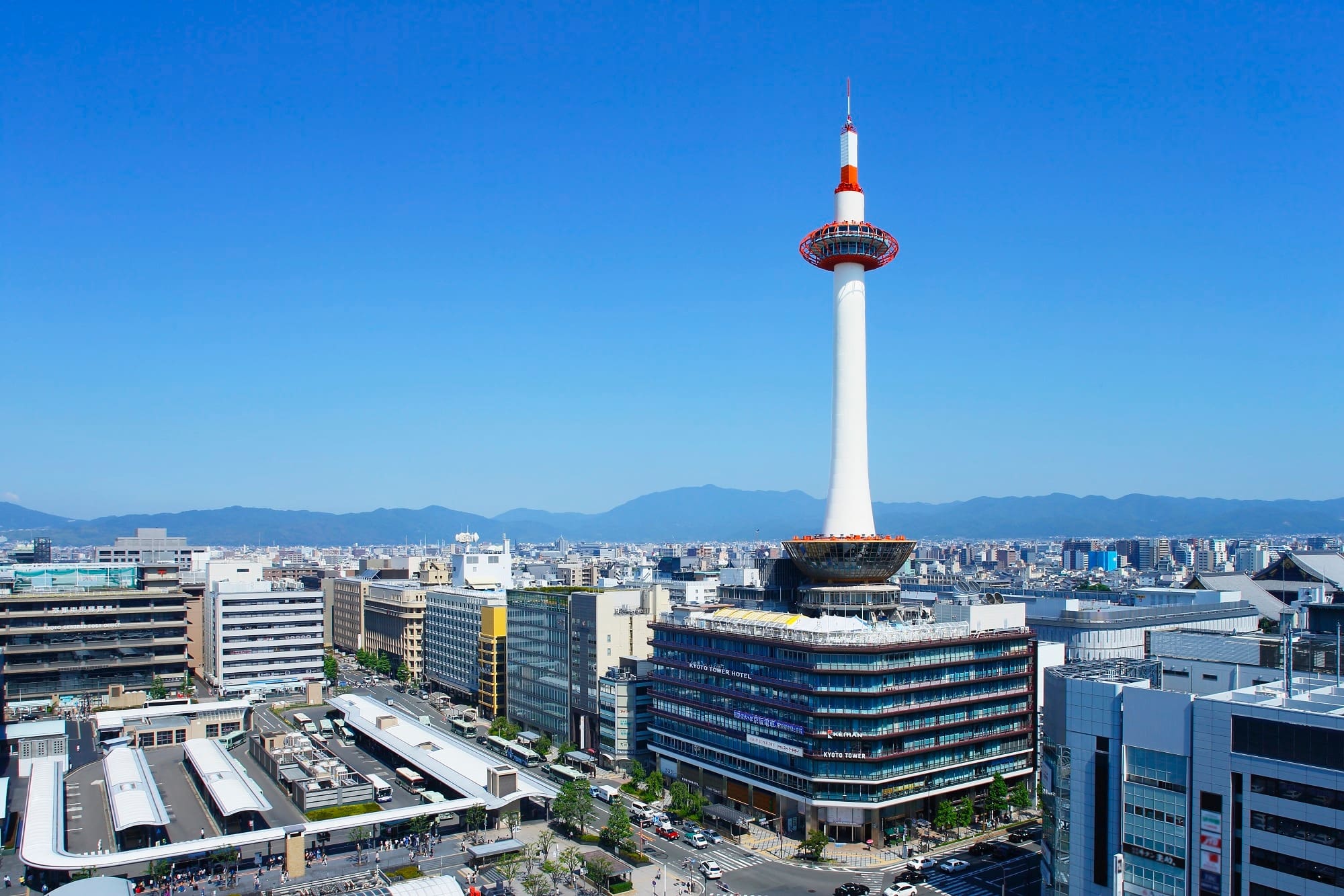 Kansai Travel Blogs 14 Kyoto Tower standing prominently above the surrounding buildings in Kyoto, Japan, against a clear blue sky.