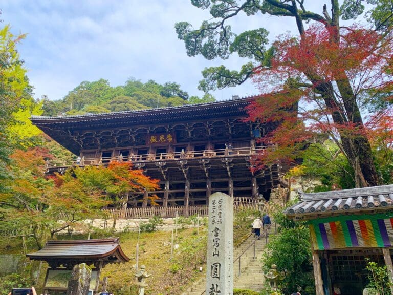 shoshayama Traditional wooden temple structure surrounded by colorful autumn foliage and stone markers in a natural setting.