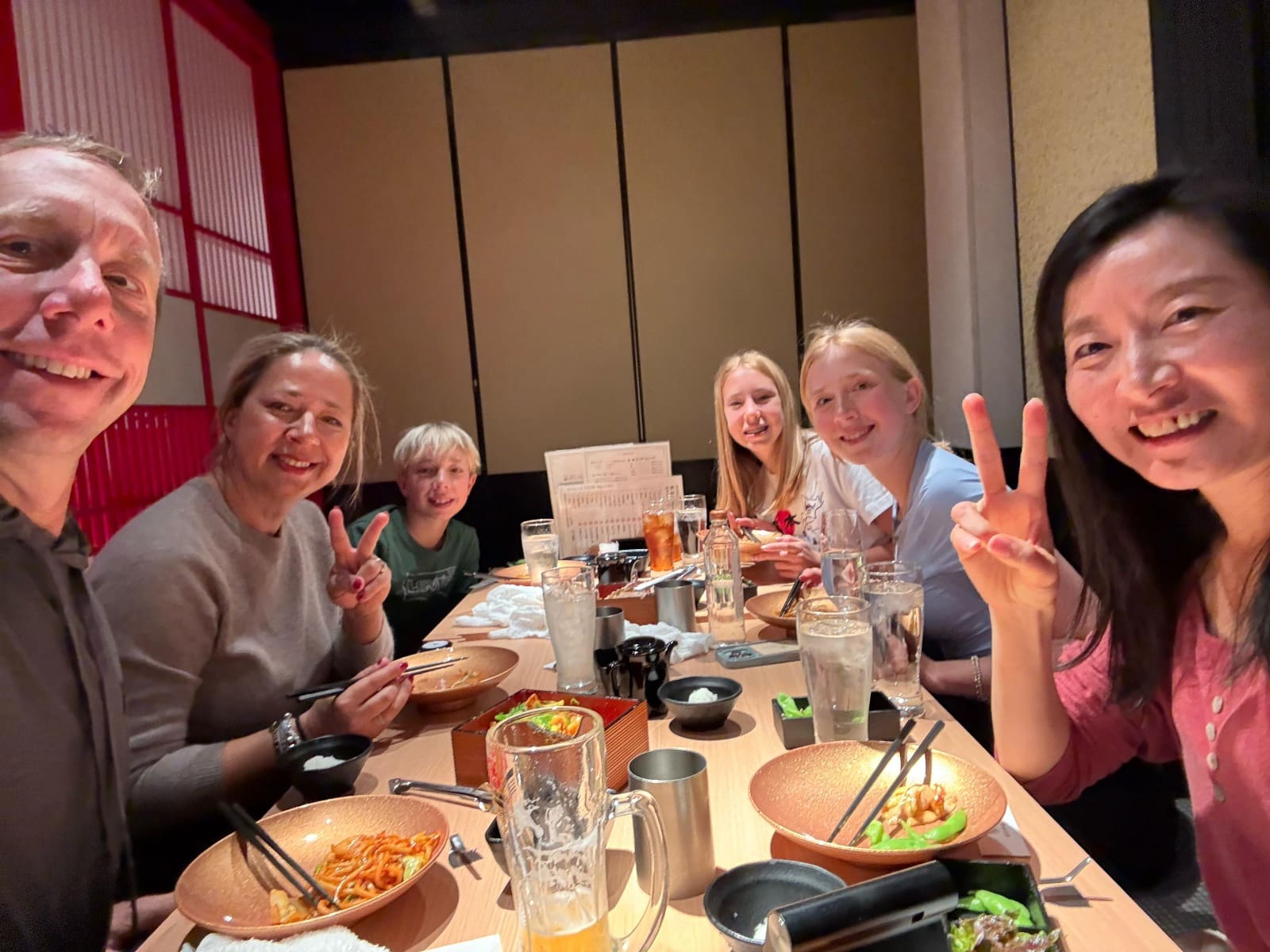 Group of six people at a dining table in a restaurant, smiling and posing for a photo.