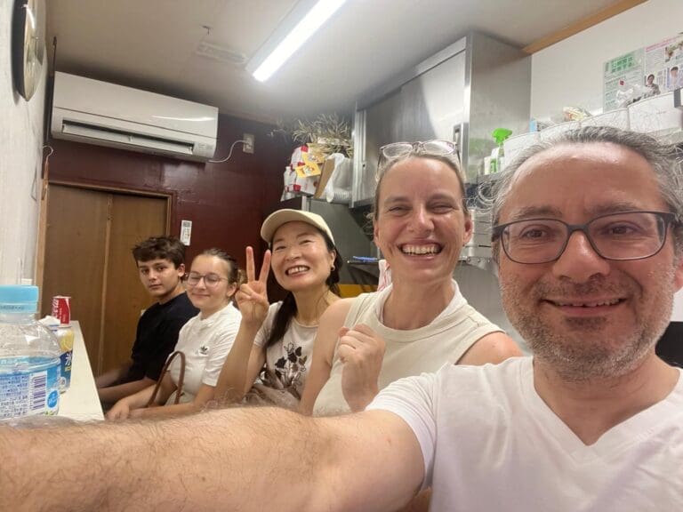 whatsapp-image-2025-07-22-at-3-30-12-pm Group of five people smiling and posing for a selfie in a casual indoor setting with a kitchen backdrop.
