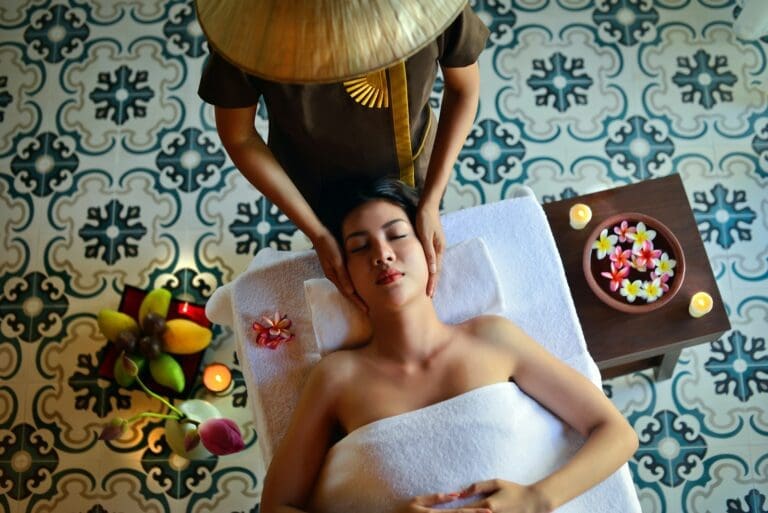 A woman receiving a massage while lying on a massage table, covered with a towel, in a serene spa setting. Massage in Osaka