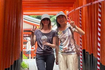 Two women posing together in a traditional Japanese torii gate pathway at a shrine.