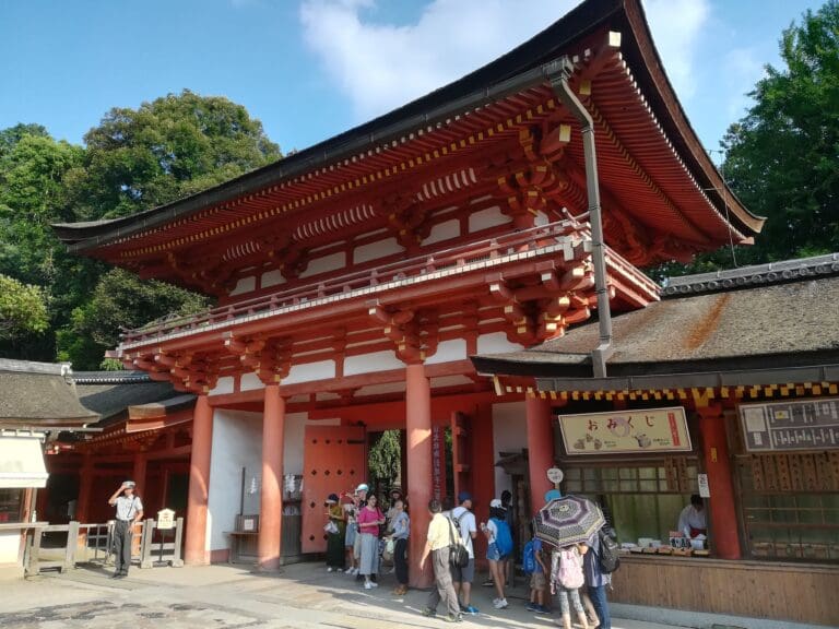 sdr-4 Entrance gate of Heian Jingu shrine with traditional architecture and visitors in front, showcasing vibrant red columns and ornate roof details.