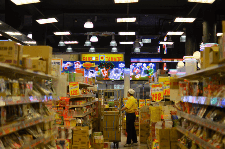 Supermarkets in Osaka, Interior view of Super Tamade grocery store with shelves of products and neon signage.