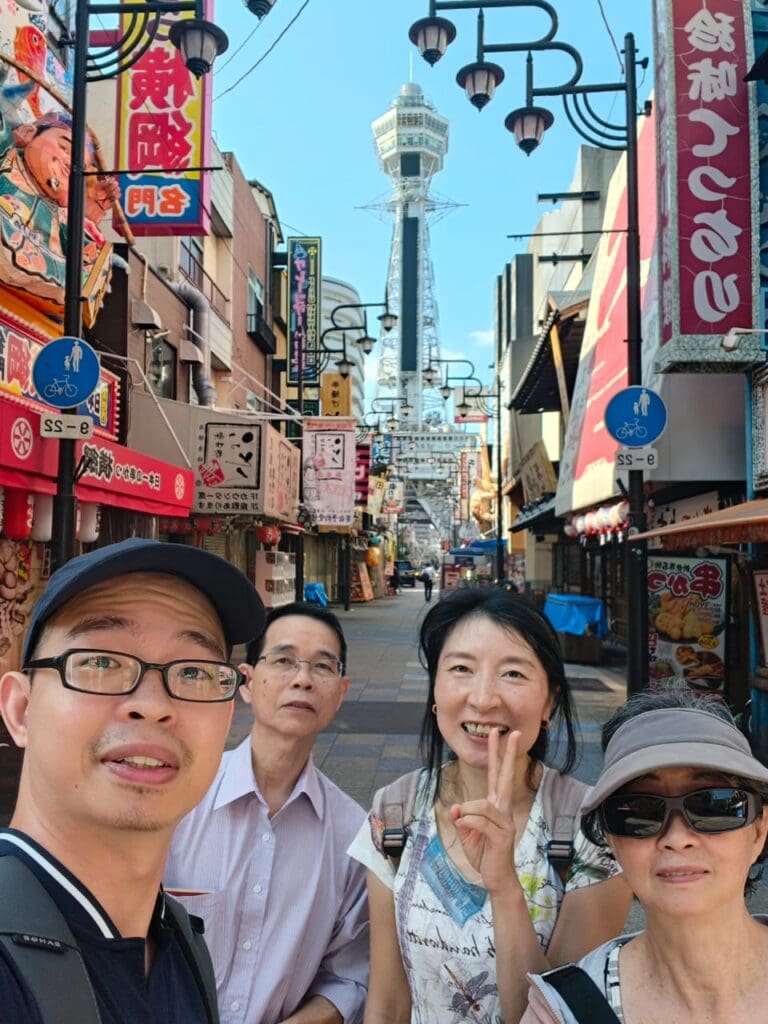 photo-with-edward-2 Group of four people posing for a selfie in an urban area with a tower in the background.