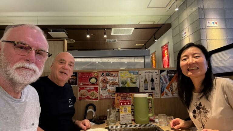 Three individuals seated at a table in a restaurant, smiling and engaging with each other.