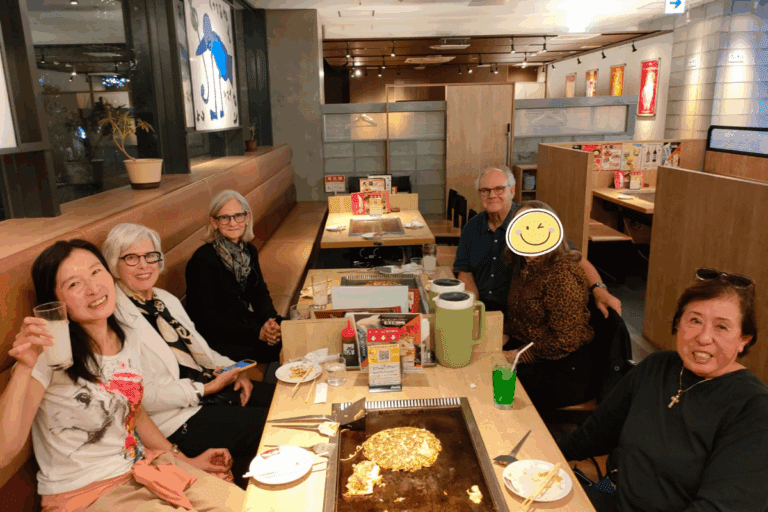 Group of five guests seated at a restaurant table enjoying a meal with drinks and food items.